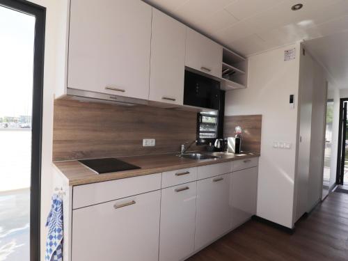 a kitchen with white cabinets and a sink at Houseboat in Lemmer with Harbor Views in Lemmer
