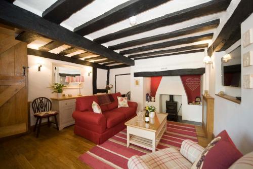 a living room with a red couch and a table at Daisy Cottage in Warwick