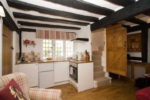 cocina con armarios blancos y techo a rayas en Daisy Cottage en Warwick