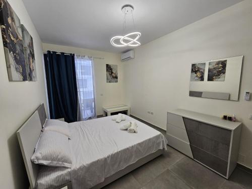 a white bedroom with a bed and a desk at Valentino Retreat in Tirana