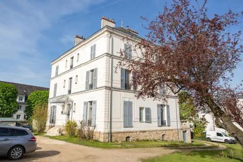 a white house with a car parked in front of it at Le studio Parisien in Boissy-Saint-Léger