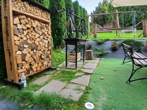 a garden with a pile of fire wood and a swing at Toporowe Izby in Groń