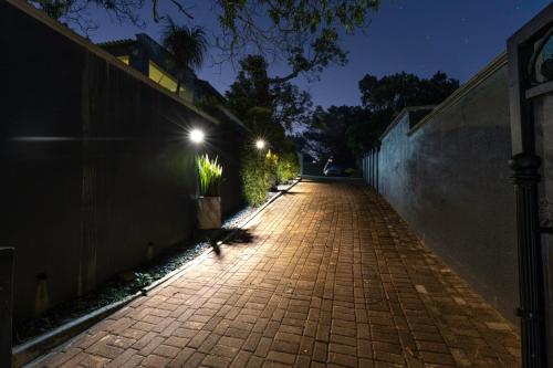 a brick walkway at night with lights on a wall at 8 On Eagle Bed & Breakfast Room 3 in Umtentweni
