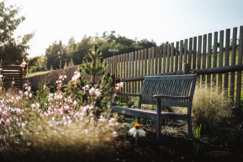 a bench in a garden with flowers and a fence at Pod Vojtěchem - soukromý wellness apartmán in Wotitz