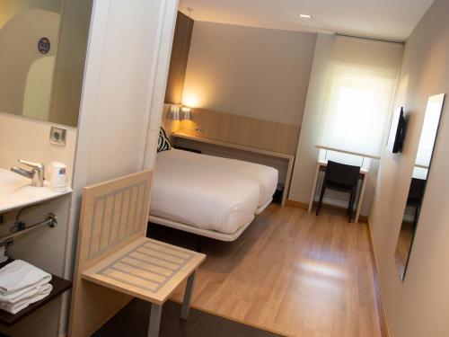 a small hotel room with a bed and a chair at Hotel Restaurante Cadosa in Soria