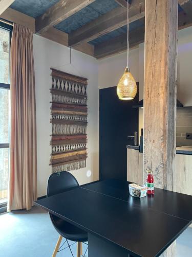 a dining room with a black table and chairs at De Koningsspil - Daar bij die Kempermolen in Breedenbroek