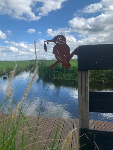 a painting of a bird on a bench next to a river at Natuurhuisje Gouderak in Gouderak