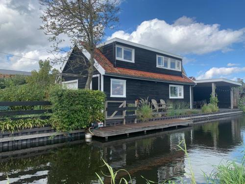 a house sitting on a dock next to a river at Natuurhuisje Gouderak in Gouderak