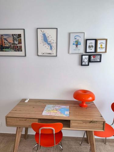 a wooden table with orange chairs and pictures on the wall at Bel appartement et place de parking au coeur d'Annecy in Annecy