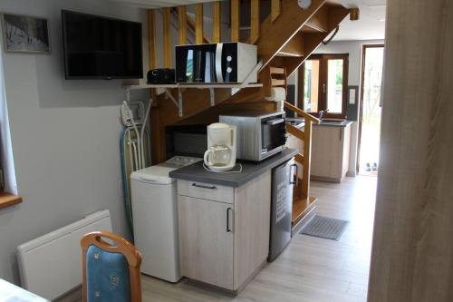 a living room with a microwave and a staircase at Garte Hiesel la maison de jardin Piscine été 2026 in Scherwiller