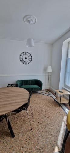 un salon avec un canapé vert et une horloge murale dans l'établissement Maison de ville Auxerroise, à Auxerre