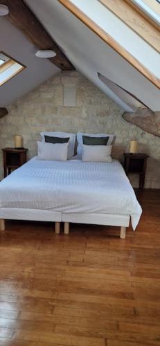 une chambre avec un lit avec des draps blancs et des oreillers dans l'établissement Maison de ville Auxerroise, à Auxerre