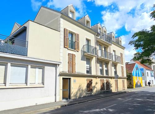 a white building with balconies on a street at Beau studio cosy entre Paris et Disneyland in Villiers-sur-Marne