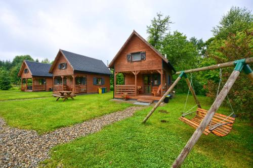 a log cabin with a swing in the yard at Domki U Szeryfa Dwernik in Dwernik