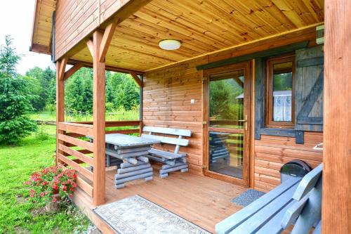 a wooden cabin with a picnic table and benches on a deck at Domki U Szeryfa Dwernik in Dwernik