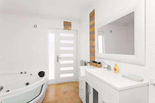 a white bathroom with a sink and a mirror at Relaxing Getaway Beachfront Access Multi Family Pets Mandurah in Mandurah