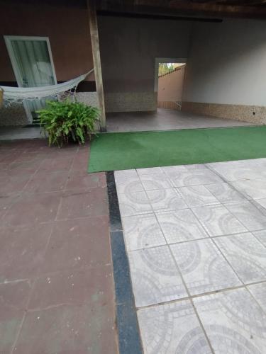 a patio with a green floor and a hammock at Casa na Praia in Jacaraípe