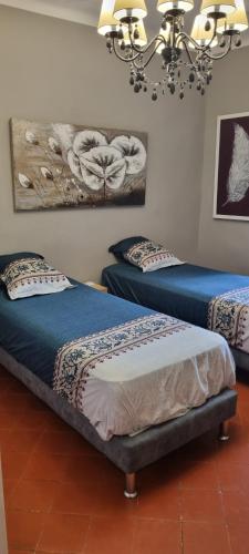 Cette chambre comprend deux lits et un lustre. dans l'établissement La Gardoise a la campagne, à Brignon