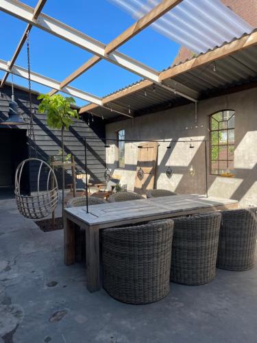 a wooden table with wicker chairs in a patio at De Koningsspil - Daar bij die Kempermolen in Breedenbroek