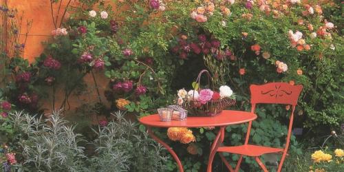 a table and chair in a garden with flowers at Hotel Mina in Hemmingen