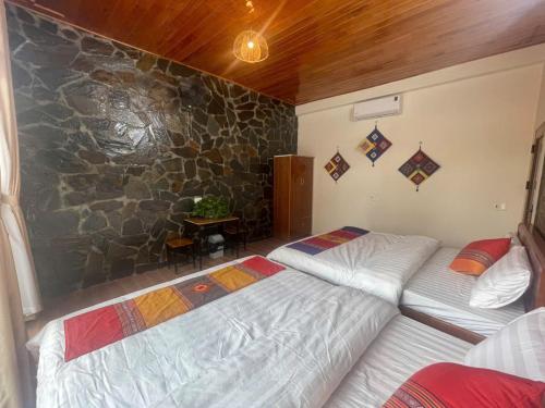 a bedroom with two beds and a stone wall at Viet Anh Mai Chau Homestay in Mai Chau