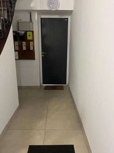 un couloir avec une porte noire et du carrelage. dans l'établissement Le petit nouveau avec Jardin, à Pont-à-Mousson