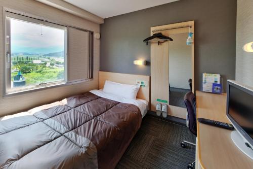 a hotel room with a bed and a window at Super Hotel Arai Niigata in Myoko
