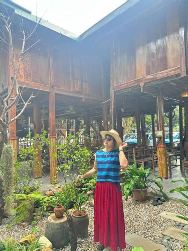 a woman wearing a hat standing in front of a building at Viet Anh Mai Chau Homestay in Mai Chau