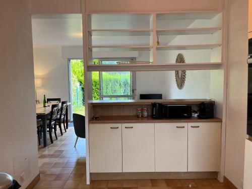 une cuisine avec des placards blancs et un lit en mezzanine dans l'établissement La maison des dunes de Kerambigorn, à Fouesnant