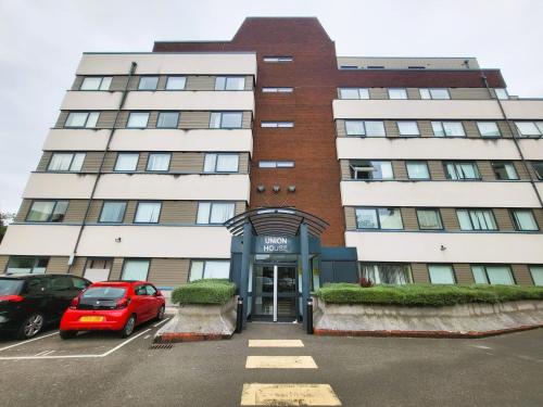 a building with a red car parked in a parking lot at London Heathrow Apartment - Hayes & Harlington in Hayes