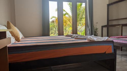 a bedroom with a bed with a large window at Aiden Homestay in Pasikuda