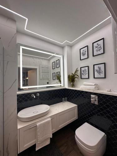 a bathroom with a sink and a toilet and a mirror at Central Park Mielno Operator Team- apartament IVO in Mielno