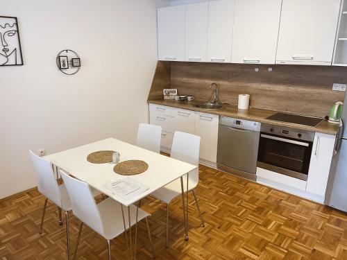 a kitchen with a white table and white cabinets at Apartment Troi in Pristina