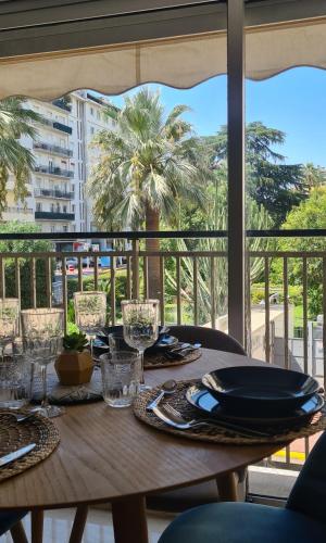 une table en bois avec des assiettes et des verres sur un balcon dans l'établissement Le Ptit Ecrin du Lerins, à Cannes