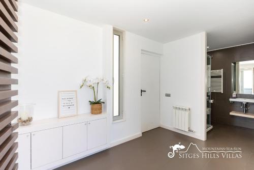 a white bathroom with a sink and a window at Stunning views to sea from Modern Villa El Mirador near Sitges in Canyelles