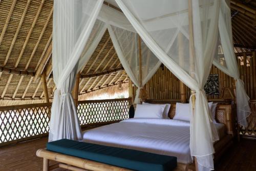 a bed in a room with a mosquito net at Pitu, a Punggul Village Escape in Sangeh