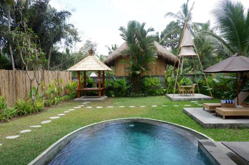 a backyard with a swimming pool and a house at Pitu, a Punggul Village Escape in Sangeh
