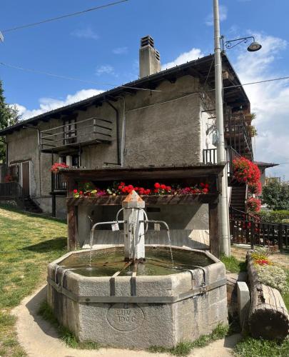 a stone fountain in front of a house at Pragelato per chi ama la natura lo sci di fondo in Pragelato