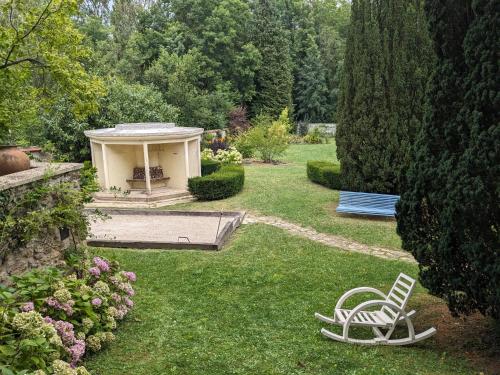 a garden with a chair and a gazebo in the grass at La Closerie in Droue-sur-Drouette