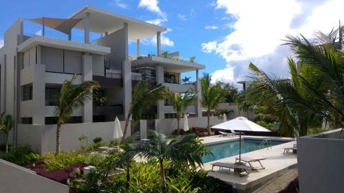 a large white building with a swimming pool and palm trees at Serenity Ocean Side in Cap Malheureux