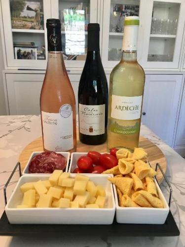 two bottles of wine and a tray of cheese and crackers at Villa Câline chambres d'hôtes in Vesseaux