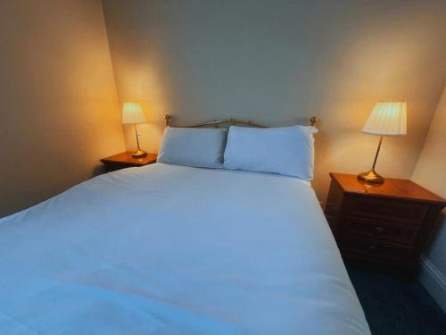 a bedroom with a large white bed with two lamps at Helen's Hotel near Wembley in London