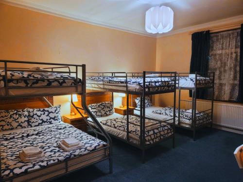 a room with three bunk beds in it at Helen's Hotel near Wembley in London