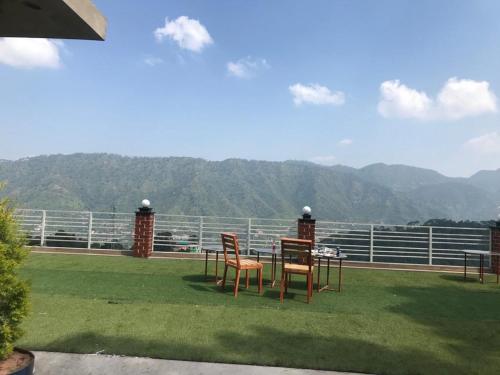 a table and chairs on a balcony with a view of mountains at host jatin kasauli crest 7o1827o7o3 in Kasauli