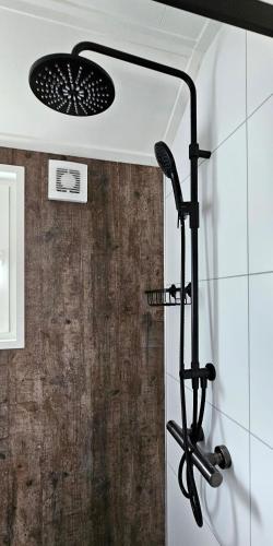 a shower with a shower head in a bathroom at Royal Resort Cosy Cabin met Hottub in Haarle