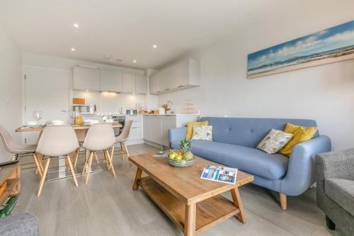 a living room with a blue couch and a table at 8 Woolacombe West - Luxury Apartment at Byron Woolacombe, only 4 minute walk to Woolacombe Beach! in Woolacombe