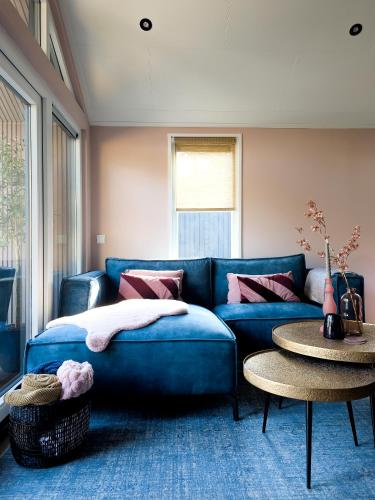 a living room with a blue couch and a table at Royal Resort Cosy Cabin met Hottub in Haarle