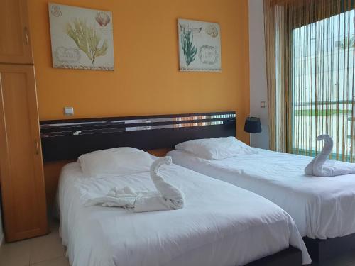 two beds in a hotel room with swans on them at Magnifique Duplex avec piscine en bord de mer in Olhos de Água