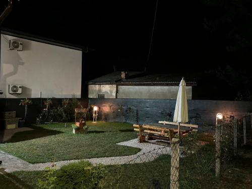 a backyard at night with a table and an umbrella at VillaH Weekend House in Visoko
