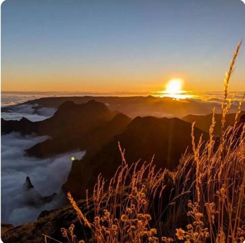 a view of the sun setting over a mountain range at Refúgio do Vale in Ribeira Brava